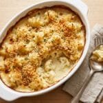 Cauliflower gratin in a white baking dish with a golden, crisp breadcrumb topping and fresh thyme
