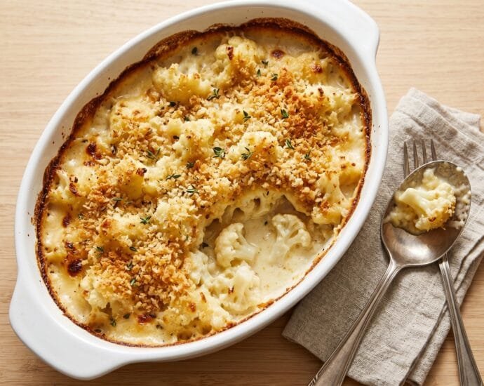 Cauliflower gratin in a white baking dish with a golden, crisp breadcrumb topping and fresh thyme