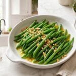 Instant Pot garlic green beans, tender-crisp and glistening with olive oil and golden garlic, in a white serving dish