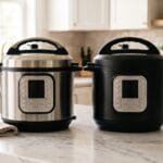 A stainless steel electric pressure cooker and a matte black one side by side on a marble counter